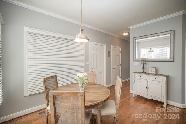 dining area with light hardwood / wood-style floors and crown molding