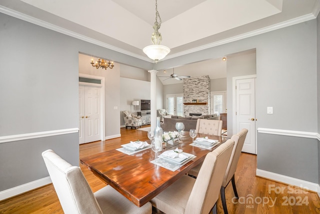 dining space with ceiling fan with notable chandelier, crown molding, vaulted ceiling, light hardwood / wood-style floors, and decorative columns