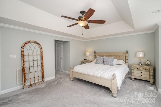 carpeted bedroom with ceiling fan, ornamental molding, and a tray ceiling