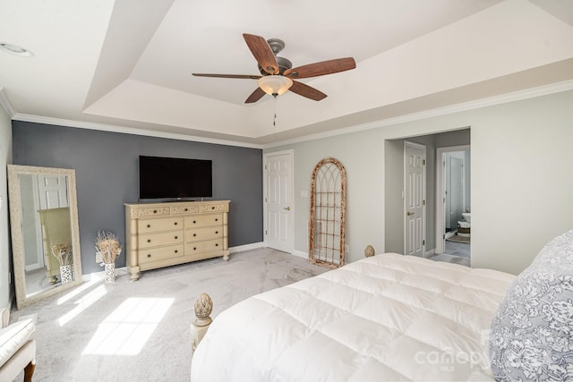 bedroom featuring ensuite bath, a tray ceiling, ceiling fan, crown molding, and carpet floors