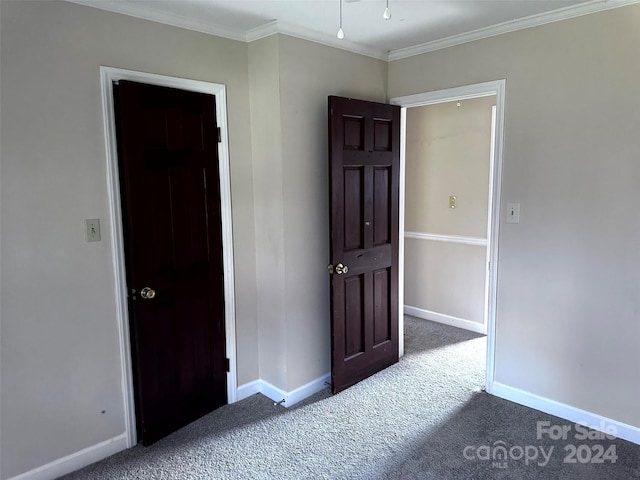 empty room featuring dark colored carpet and crown molding