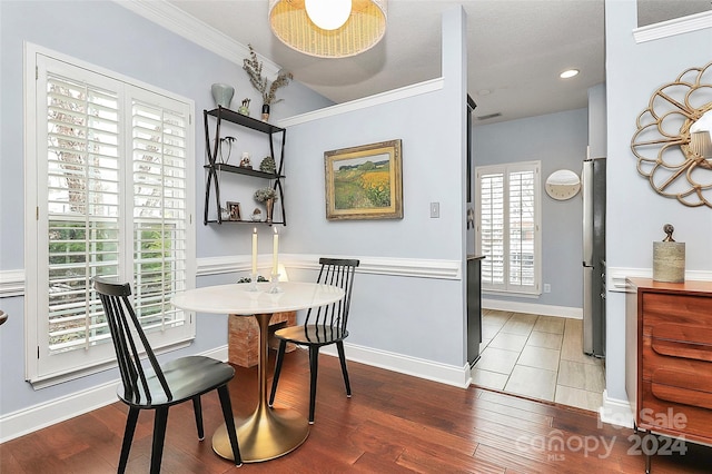 dining space with hardwood / wood-style floors, a textured ceiling, ornamental molding, and a healthy amount of sunlight