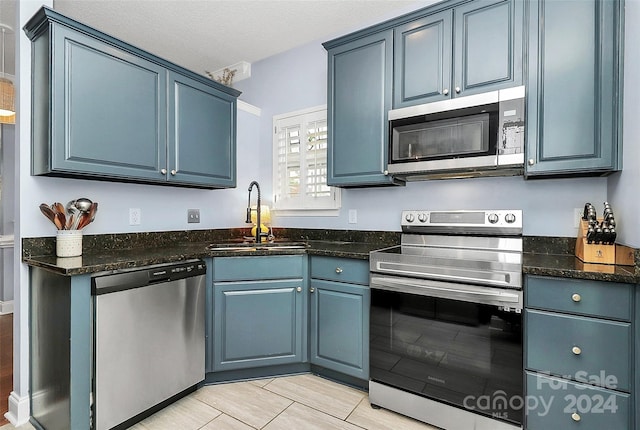 kitchen with blue cabinets, sink, a textured ceiling, appliances with stainless steel finishes, and light hardwood / wood-style floors