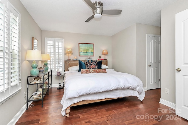 bedroom with a textured ceiling, ceiling fan, and dark wood-type flooring