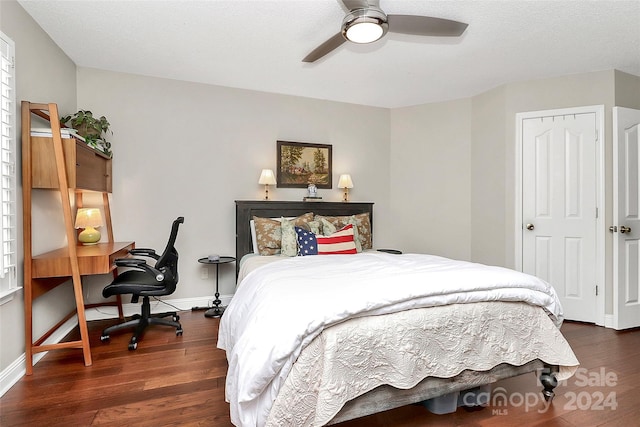 bedroom with a textured ceiling, ceiling fan, and dark wood-type flooring