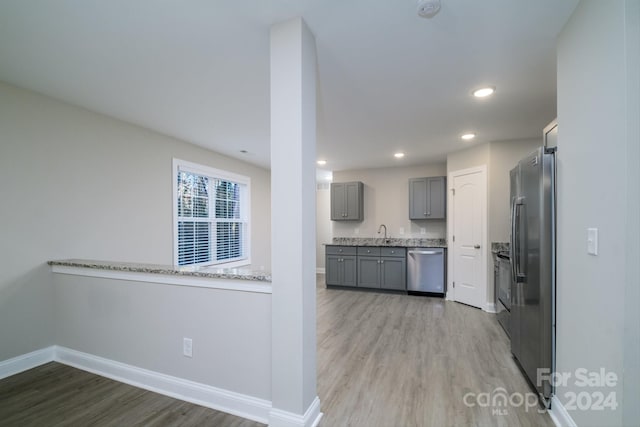 kitchen featuring kitchen peninsula, appliances with stainless steel finishes, sink, light hardwood / wood-style flooring, and gray cabinets