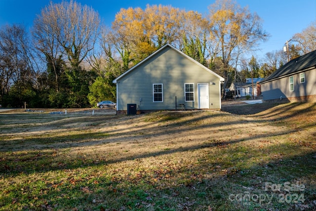 rear view of property featuring a lawn and central AC unit