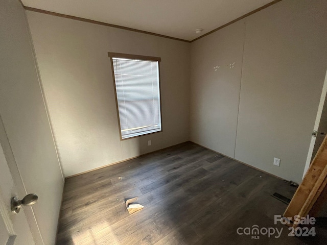 empty room featuring dark hardwood / wood-style floors and ornamental molding