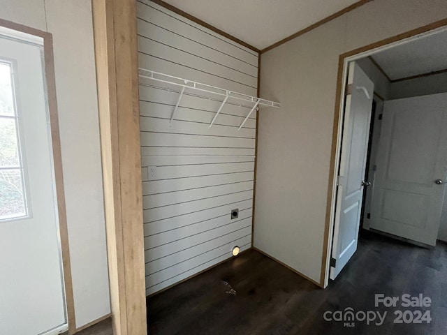 clothes washing area featuring dark hardwood / wood-style floors, wood walls, and crown molding