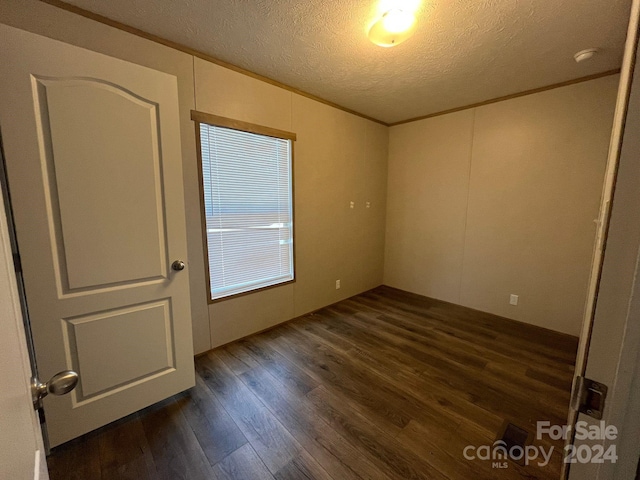 unfurnished room featuring a textured ceiling and dark hardwood / wood-style floors