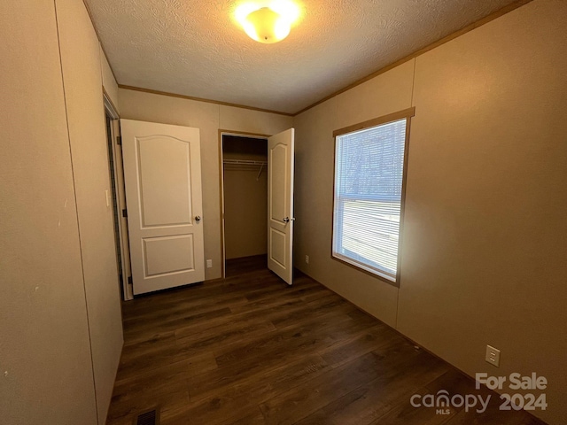 unfurnished bedroom featuring a closet, dark hardwood / wood-style flooring, and a textured ceiling