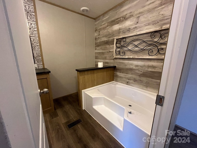 bathroom featuring hardwood / wood-style floors, a bath, wooden walls, and a textured ceiling