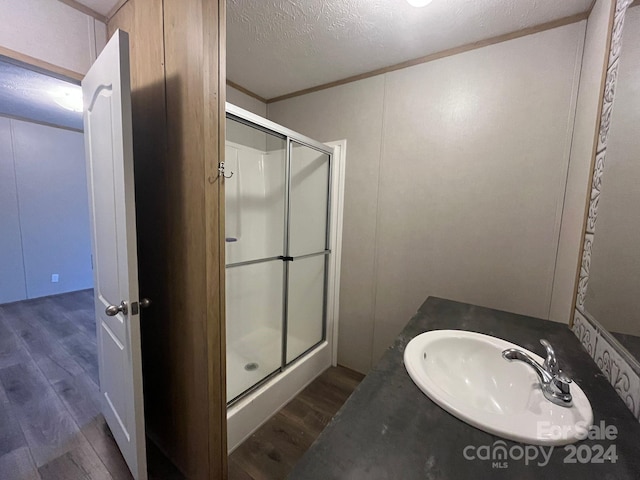 bathroom featuring hardwood / wood-style floors, vanity, a shower with door, and a textured ceiling