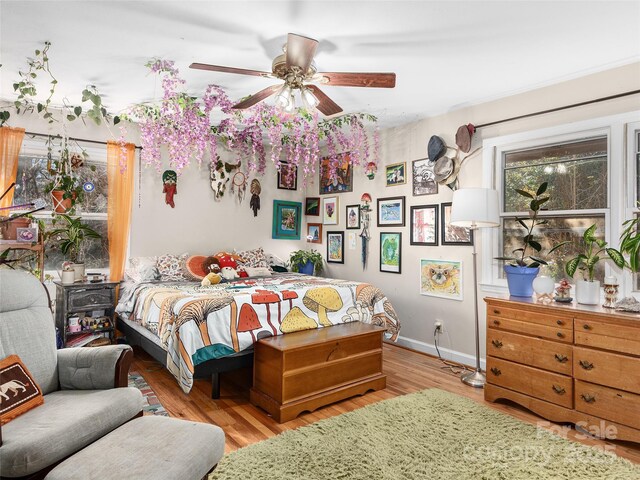 bedroom with baseboards, light wood-style floors, and a ceiling fan