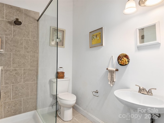 bathroom with toilet, a sink, tile patterned flooring, and a tile shower