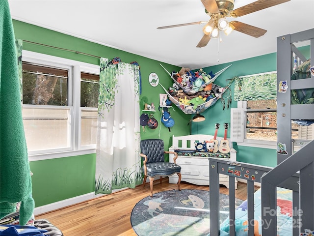 bedroom featuring baseboards, wood finished floors, and a ceiling fan