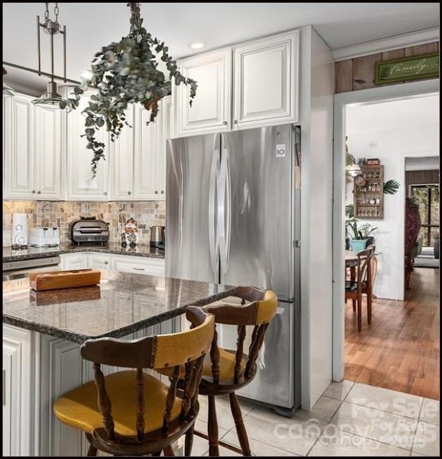 81 Jericho Dr, Tryon, NC 28782 - kitchen featuring freestanding refrigerator, a breakfast bar, white cabinets, tasteful backsplash, and dark stone countertops