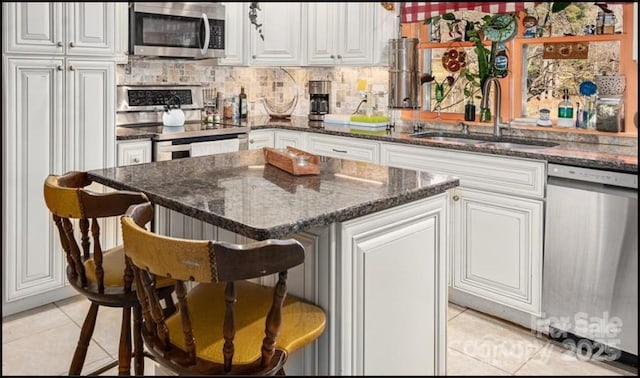 81 Jericho Dr, Tryon, NC 28782 - kitchen with stainless steel appliances, light tile patterned flooring, white cabinets, a kitchen breakfast bar, and a kitchen island