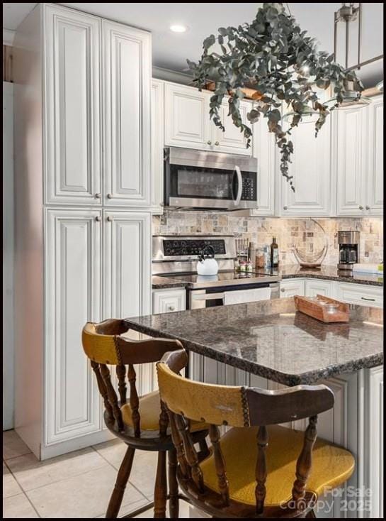 81 Jericho Dr, Tryon, NC 28782 - kitchen featuring stainless steel appliances, a kitchen breakfast bar, backsplash, light tile patterned floors, and white cabinets