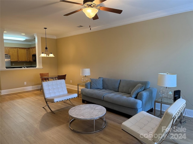 living room featuring ceiling fan with notable chandelier, light wood-type flooring, and ornamental molding