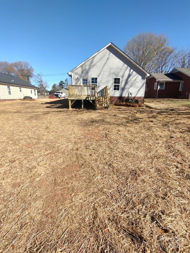 back of property featuring a yard and a wooden deck