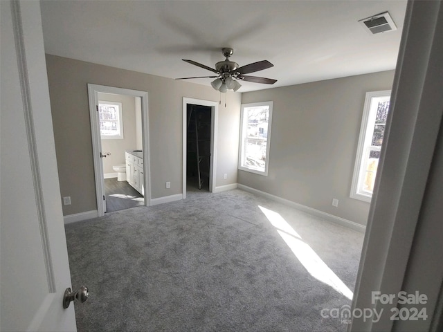 unfurnished bedroom with connected bathroom, ceiling fan, a spacious closet, a closet, and carpet