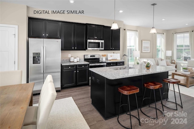 kitchen with dark hardwood / wood-style flooring, a breakfast bar, stainless steel appliances, sink, and decorative light fixtures