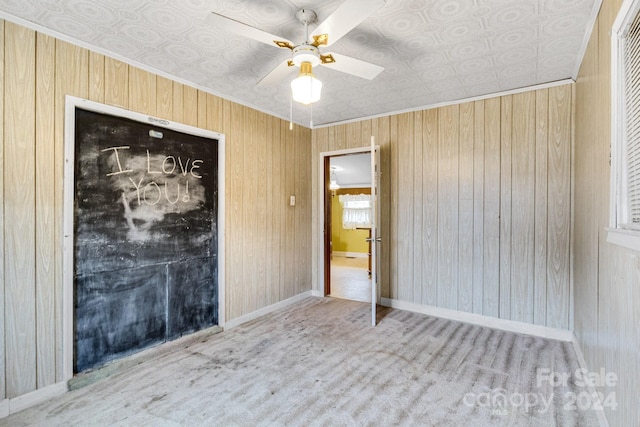 unfurnished bedroom with ceiling fan, light colored carpet, and wooden walls