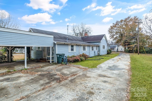 back of property with a carport and a lawn