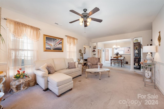 carpeted living room featuring ceiling fan with notable chandelier and decorative columns