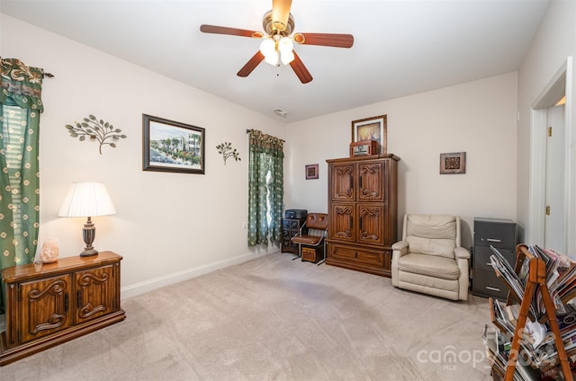 living area featuring light carpet and ceiling fan