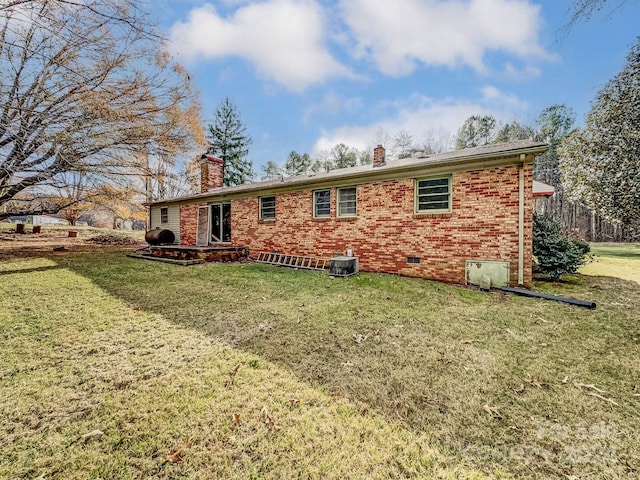 back of property with central AC and a lawn