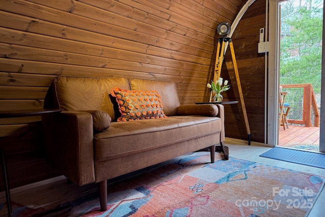 sitting room with wooden walls and vaulted ceiling