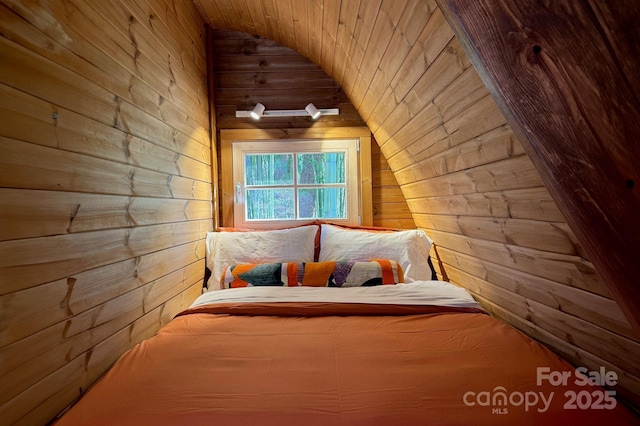 unfurnished bedroom with lofted ceiling and wood walls