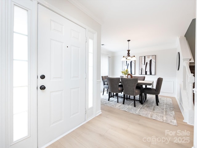 entryway featuring a notable chandelier, crown molding, and light hardwood / wood-style floors