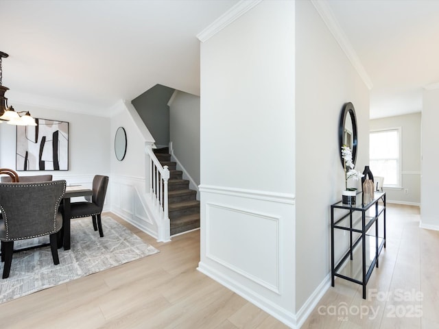 dining room with ornamental molding, a chandelier, and light hardwood / wood-style flooring