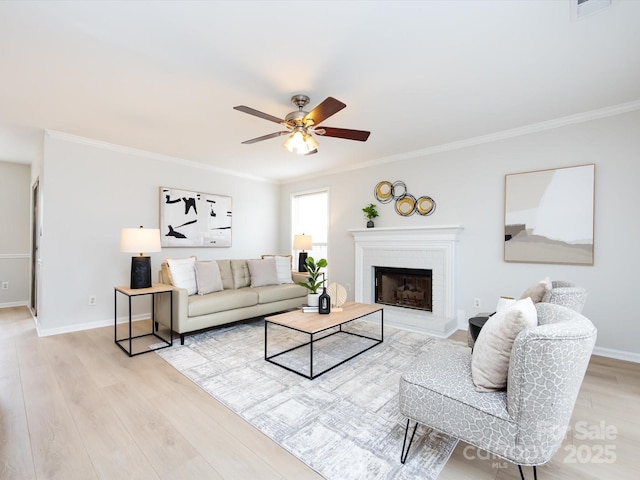 living room featuring crown molding, ceiling fan, a brick fireplace, and light hardwood / wood-style flooring