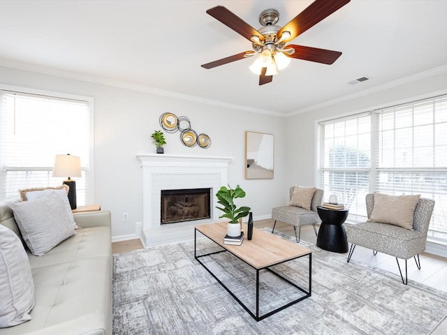 living room featuring plenty of natural light, ornamental molding, and ceiling fan