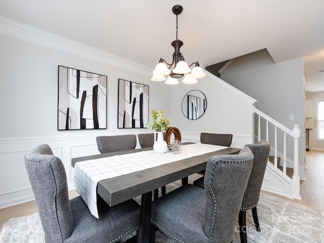 dining space with ornamental molding, light hardwood / wood-style floors, and a chandelier