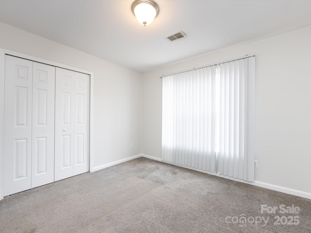 unfurnished bedroom featuring light colored carpet and a closet