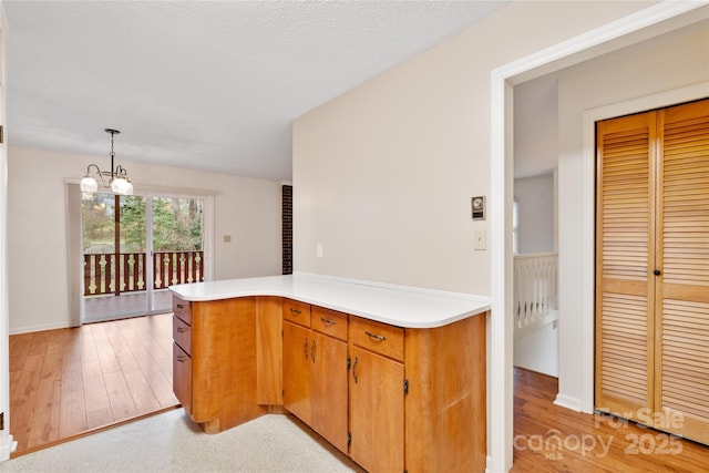 kitchen with a textured ceiling, kitchen peninsula, hanging light fixtures, and a chandelier