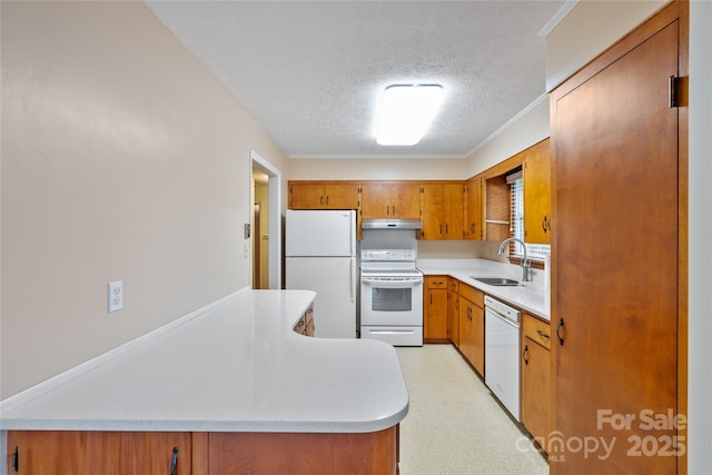 kitchen with a textured ceiling, kitchen peninsula, white appliances, and sink