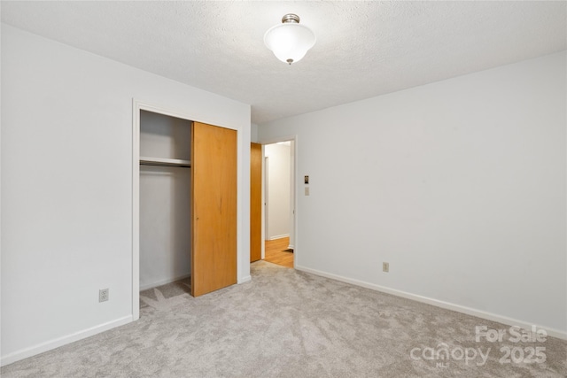 unfurnished bedroom with a textured ceiling, light colored carpet, and a closet