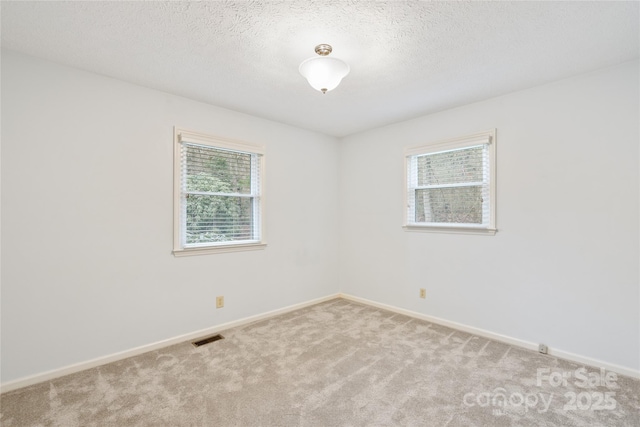 carpeted empty room with a textured ceiling