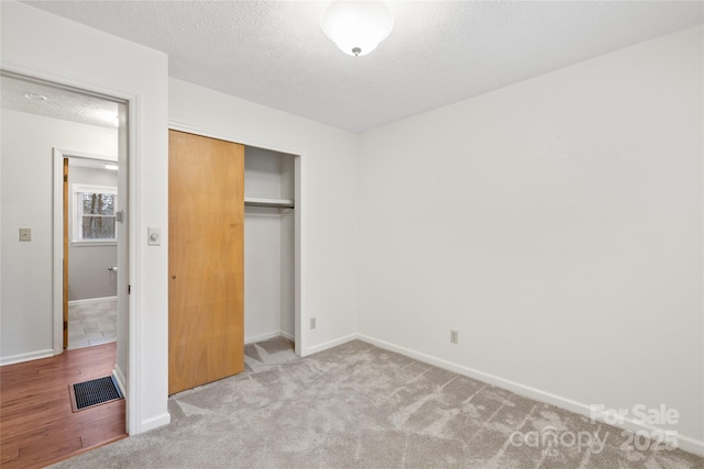 unfurnished bedroom with a textured ceiling, light carpet, and a closet