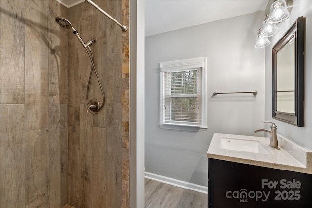 bathroom featuring hardwood / wood-style floors, vanity, and a tile shower