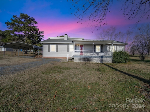 view of front of property featuring a yard, covered porch, and a carport