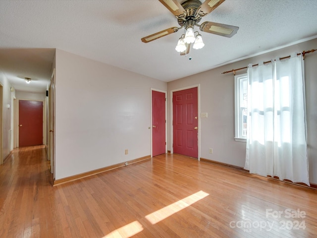 empty room with a textured ceiling, light hardwood / wood-style flooring, and ceiling fan