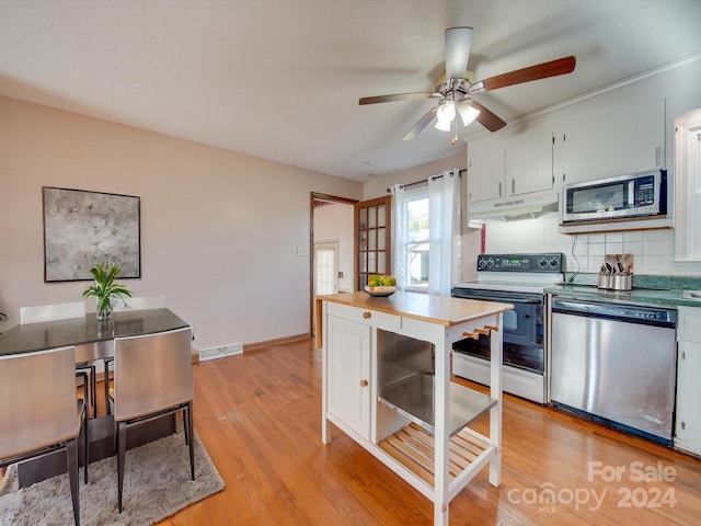 kitchen with appliances with stainless steel finishes, tasteful backsplash, ceiling fan, white cabinets, and light hardwood / wood-style floors