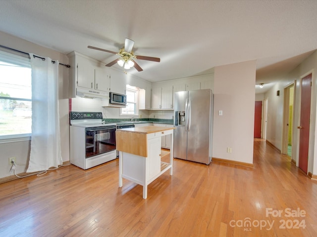 kitchen featuring ceiling fan, stainless steel appliances, white cabinets, a kitchen island, and light wood-type flooring